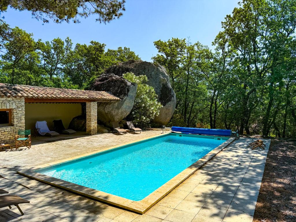 une piscine devant une maison avec un rocher dans l'établissement Mas provençal à Gordes avec piscine - Roc de Tuaran, à Gordes