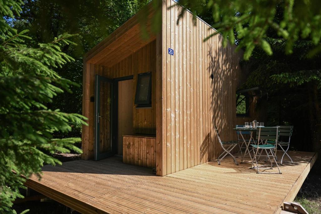 a small wooden house with a table on a deck at Green Tiny Village Harz - Tiny House Nook 20 in Osterode