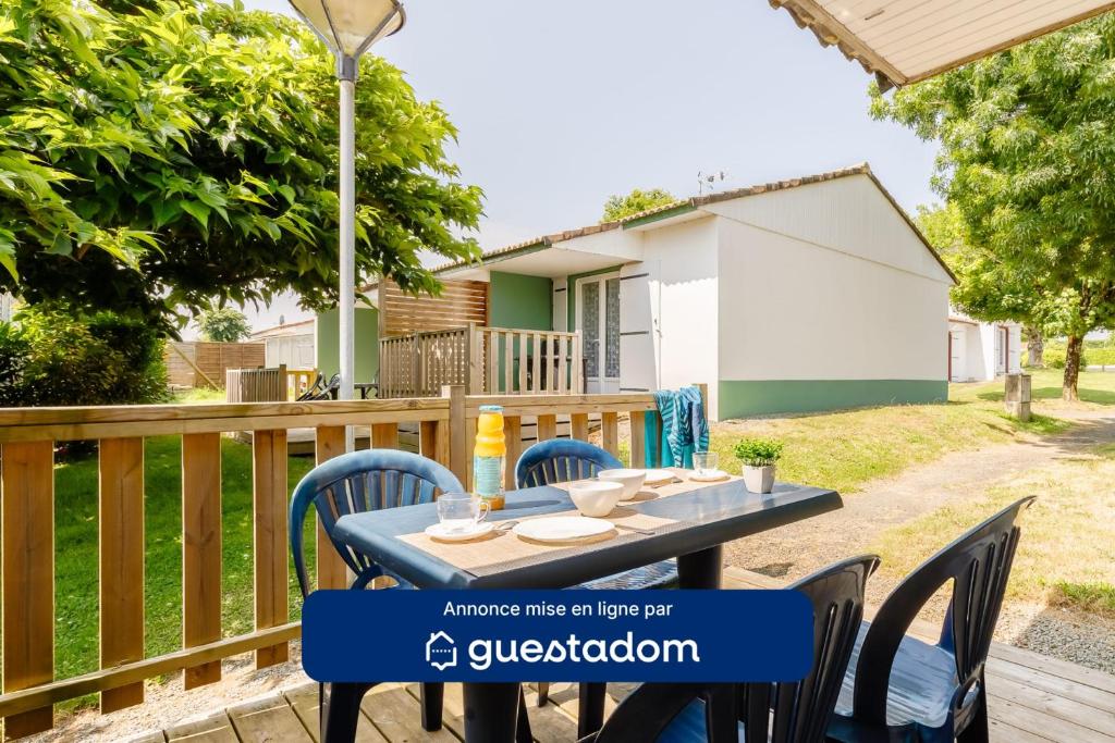 une table et des chaises sur une terrasse avec une maison en arrière-plan dans l'établissement 24 - Le Paradisier - Village vacances, à Maché