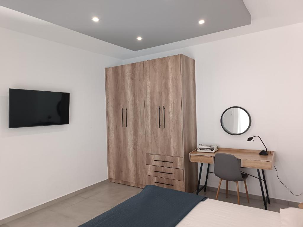 een slaapkamer met een bureau en een houten kast bij Platanou 21 Apartments in Kremasti