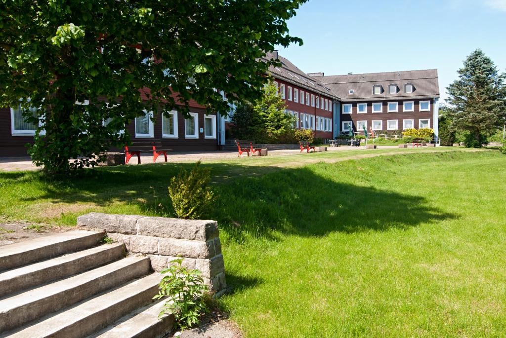 a building with a tree and stairs in front of a building at BSW Ferienwohnungen Brockenblick in Schulenberg im Oberharz