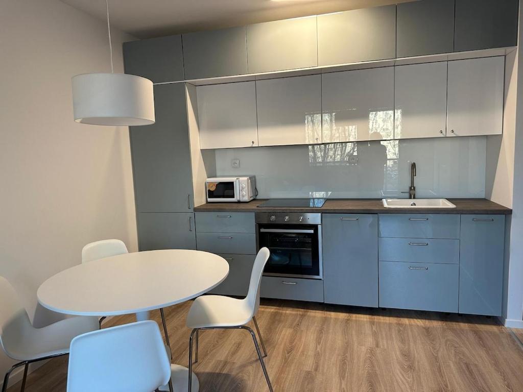 cocina con mesa blanca, sillas y fregadero en New Cozy Free Parking apartment, en Bratislava