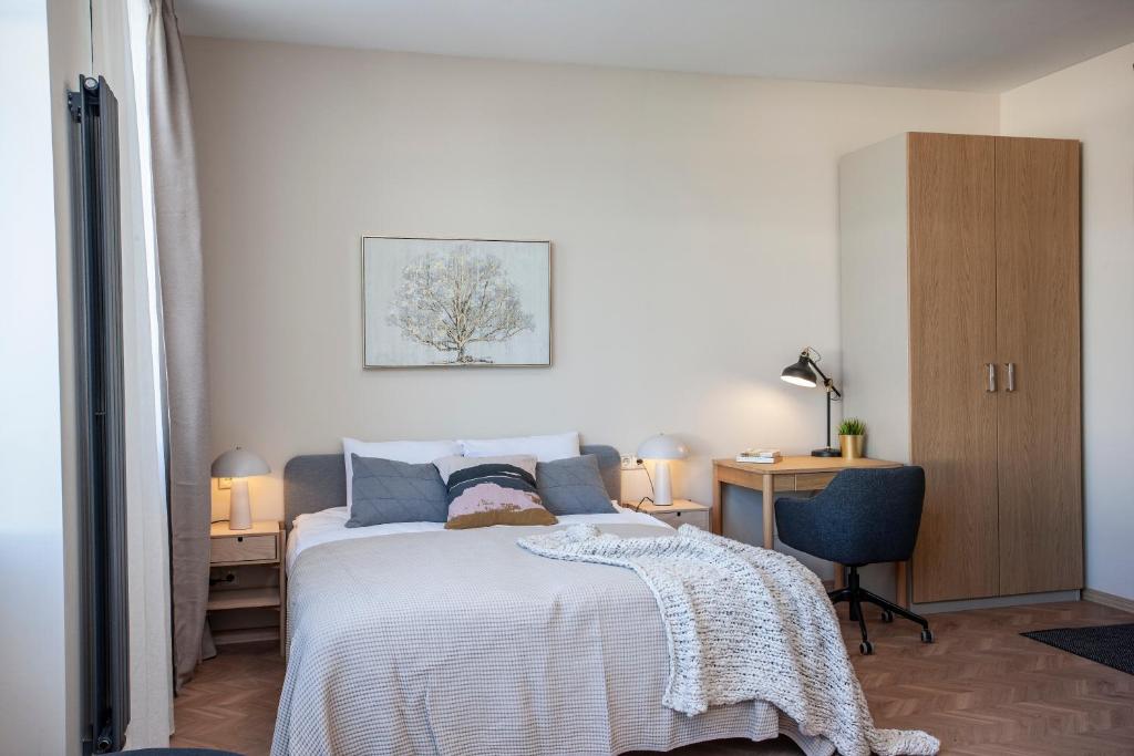 a bedroom with a bed and a desk and a chair at Upisa Apartments in Riga