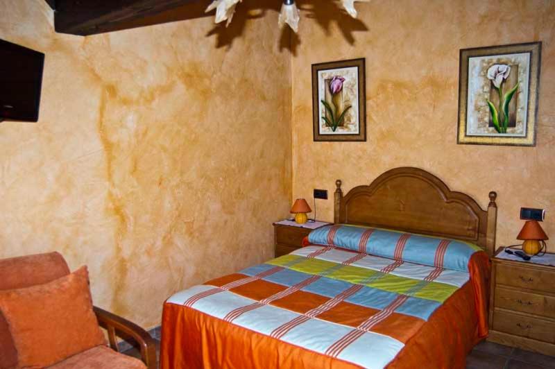 a bedroom with a bed and a chair at Casa Rural Dos Infantas Las Lilas in Valdespino