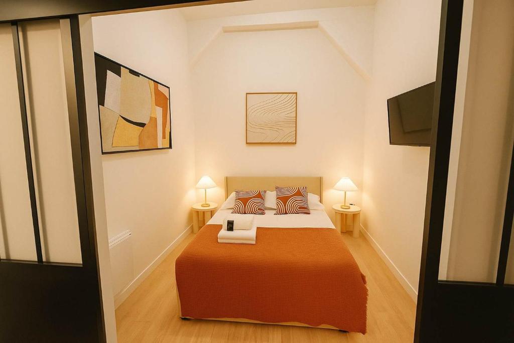 - une chambre avec un lit doté de draps et d'oreillers orange dans l'établissement 2 pieces avec mezzanine et deco design - Paris 9, à Paris