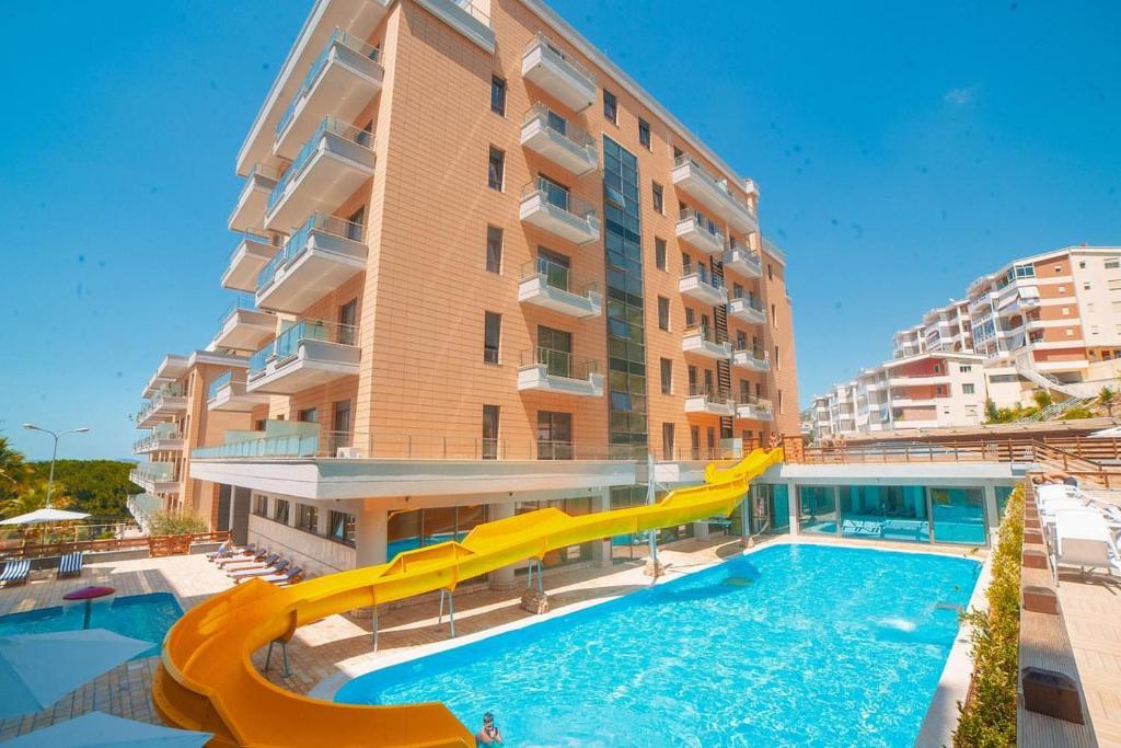 una piscina con un tobogán frente a un edificio en Lovely Apartment, en Vlorë