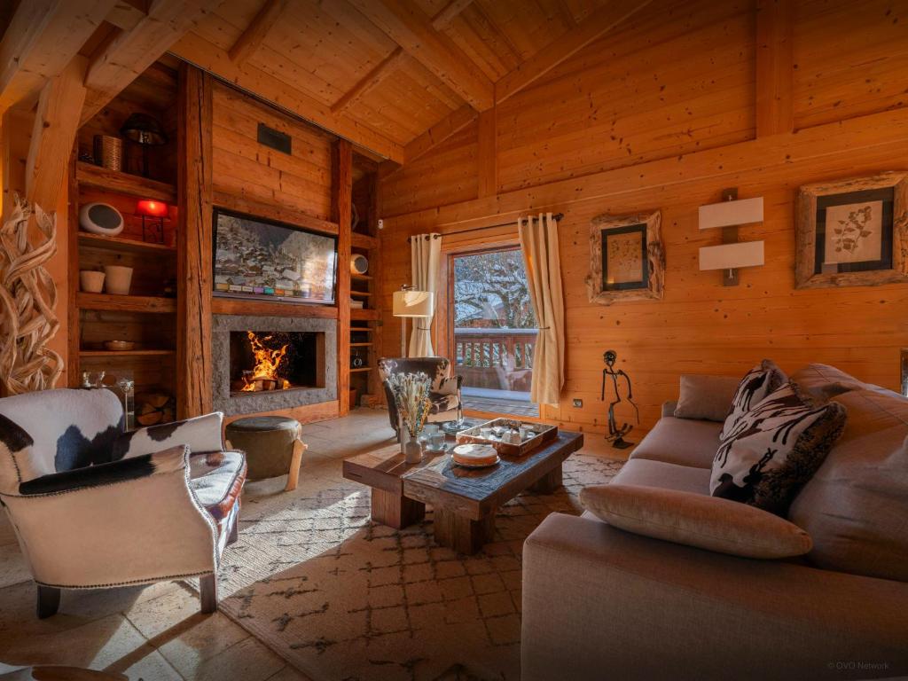 a living room with a couch and a table and a fireplace at Chalet Le San Marco - OVO Network in La Clusaz