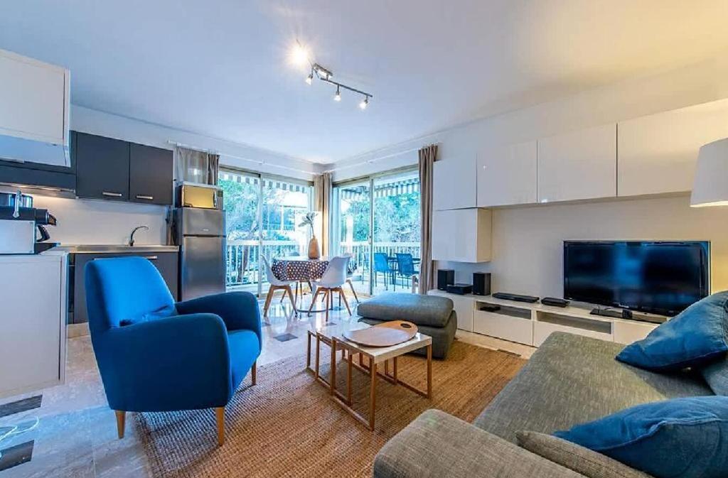 un salon avec un canapé bleu et une cuisine dans l'établissement L'ESTEREL avec piscine et grand balcon vue mer aperçu, à Cannes