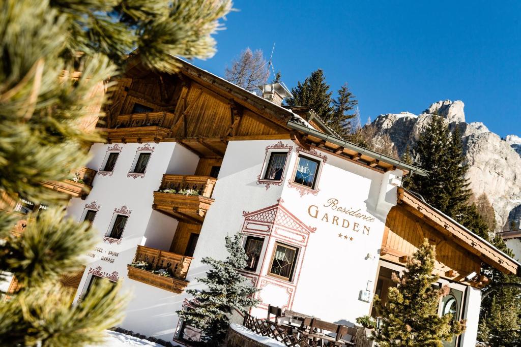 a building in the mountains with trees in front of it at Suites Hotel Garden in Selva di Val Gardena