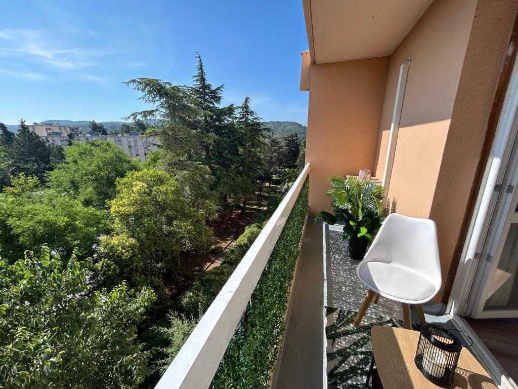 Elle comprend un balcon avec une chaise blanche et des arbres. dans l'établissement T1 Aix-en-Provence, à Aix-en-Provence