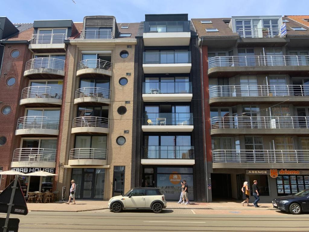 a car parked in front of a tall building at La madeleine in De Panne