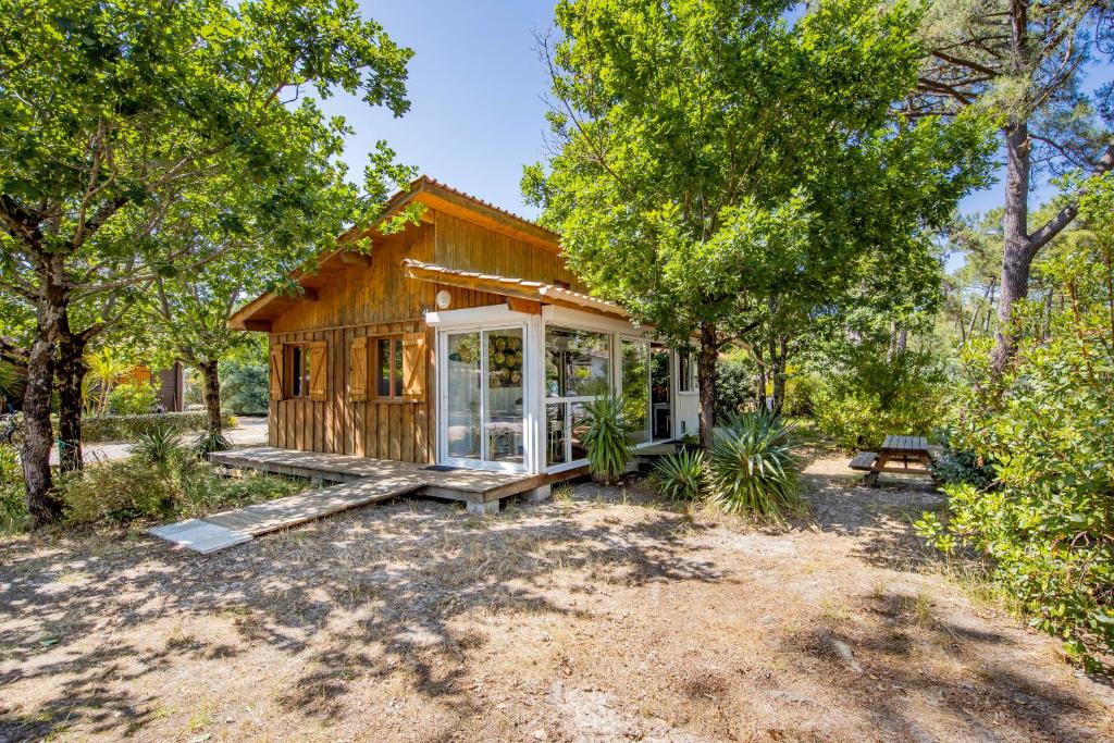 eine kleine Hütte im Wald mit einer Bank und Bäumen in der Unterkunft Bungalow Californie 48 in Vendays-Montalivet