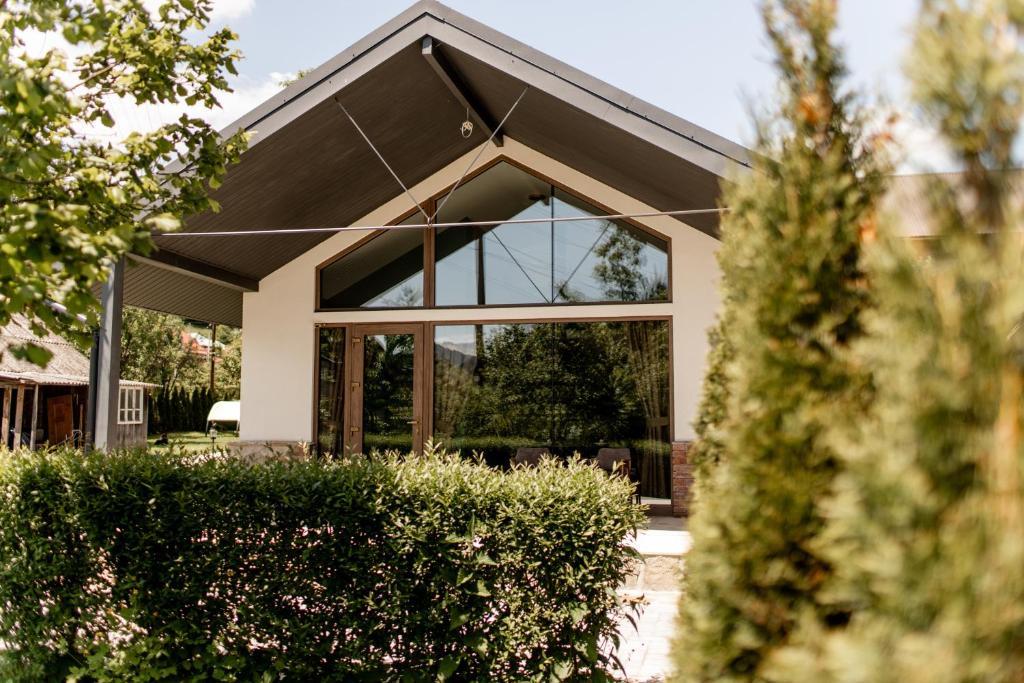 une maison avec des fenêtres en verre et un toit dans l'établissement Kovalska Sadyba, à Slavsko