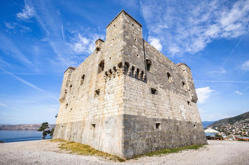 a large stone building next to a body of water at Apartments Goldie in Senj