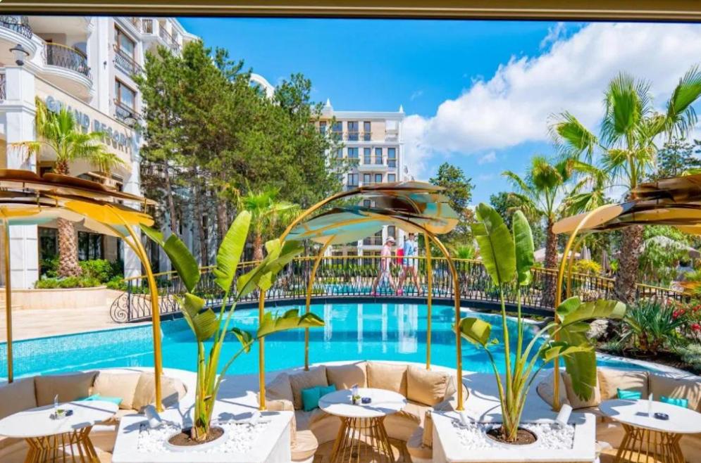 a hotel patio with tables and a swimming pool at Harmony Suites Grand Resort 16 in Sunny Beach