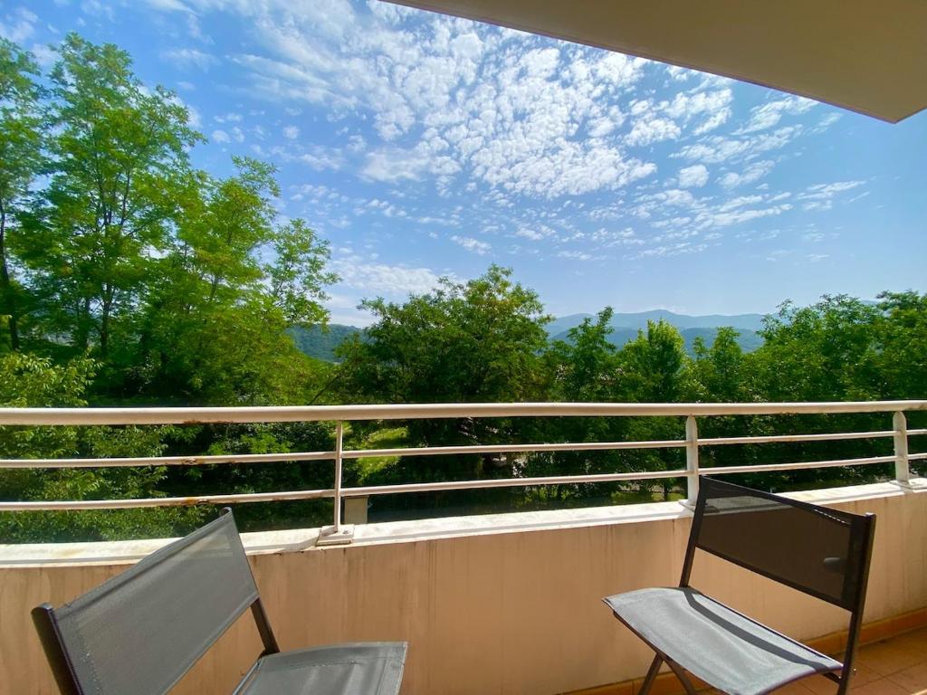 two chairs on a balcony with a view of trees at Cozy apartment in Château-Arnoux-Saint-Auban