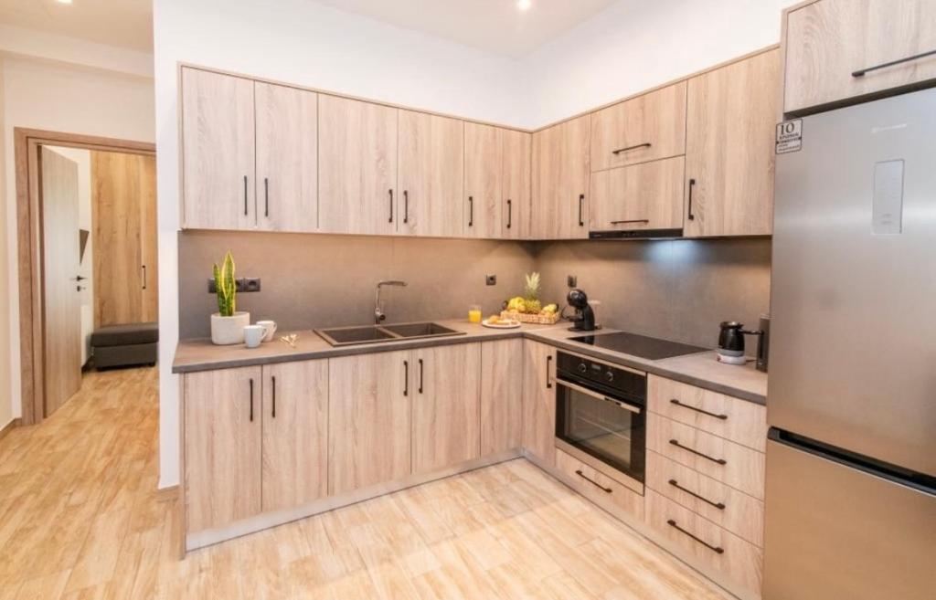 a kitchen with wooden cabinets and stainless steel appliances at Pnoe Home Tinos in Tinos