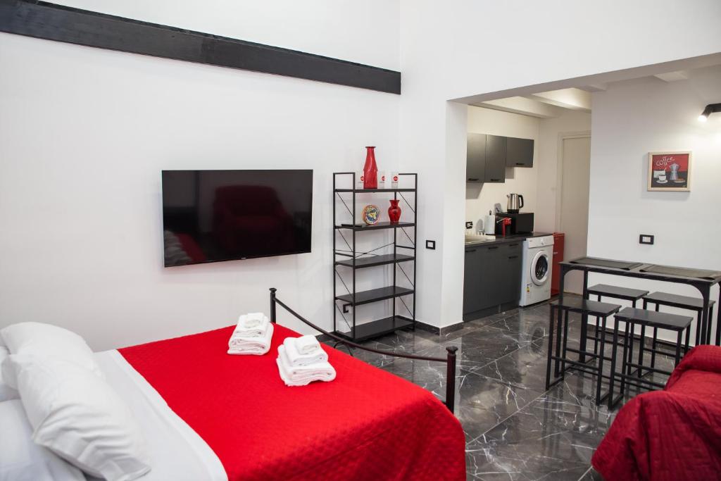 a living room with a red bed and a kitchen at 3 Rooms Catania - Vulcano bright independent studio apartment in Catania
