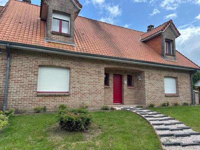 una casa in mattoni con una porta rossa e un cortile di La Maison des Oiseaux Résidence Pernes en Artois a Pernes