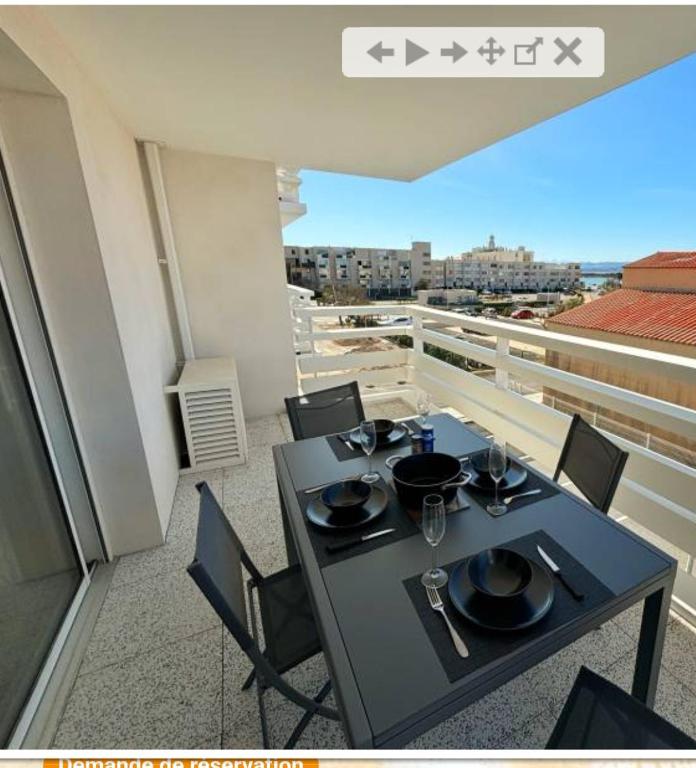 une table noire et des chaises sur un balcon dans l'établissement T2 500m de la plage Clim parking privé, à Leucate-Plage