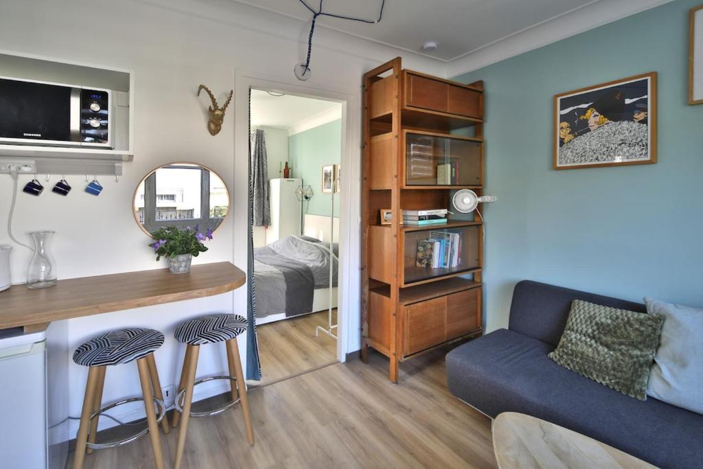 un salon avec un canapé bleu et une chambre dans l'établissement A cozy hideaway just 20 minutes from Paris, à Sartrouville