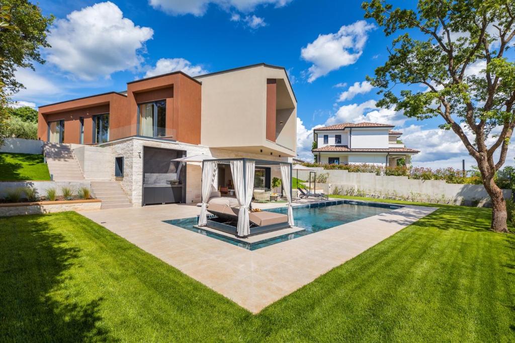 a house with a swimming pool in front of a yard at Villa Mol by Villsy - with private pool, sauna, jacuzzi in Baderna