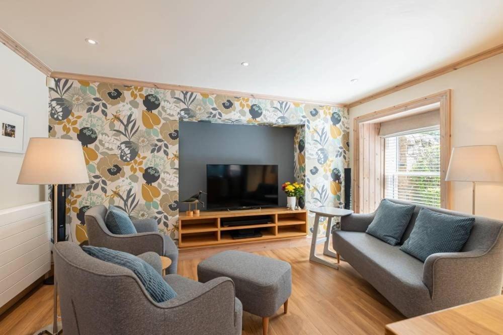 a living room with a couch and chairs and a television at Little Juniper Lodge in Edinburgh