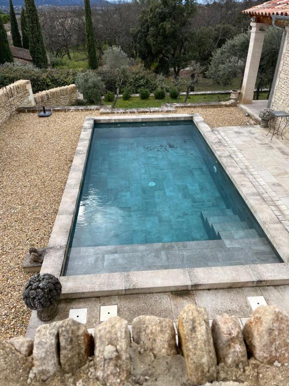 una piscina con acqua blu in un cortile di Maison dans un hameau avec piscine a Gordes