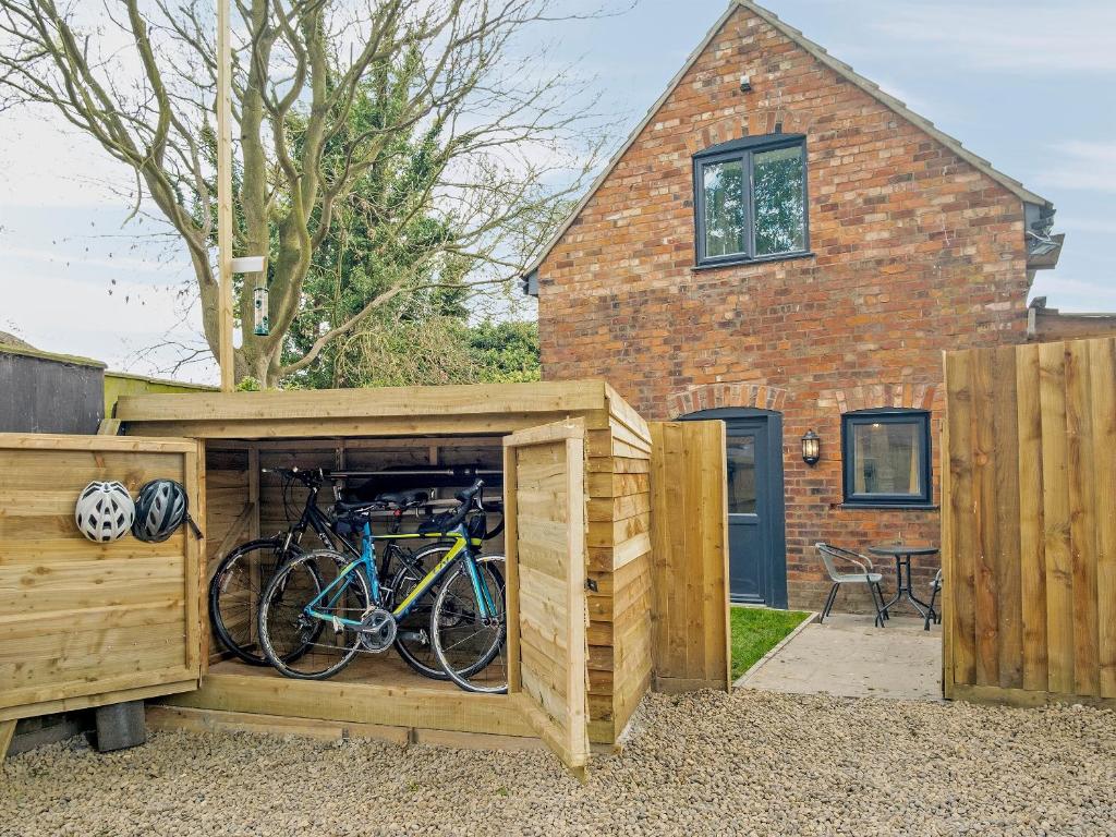 un hangar en bois avec des vélos à l'intérieur devant une maison dans l'établissement Coley Cottage, à Wainfleet All Saints
