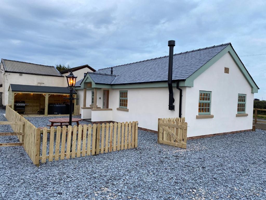a white house with a wooden fence in front of it at Pointer Cottage in Preesall
