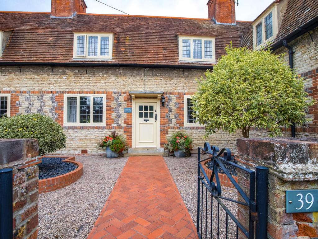 a brick house with a white door and a driveway at Dulcie Cottage in Benson