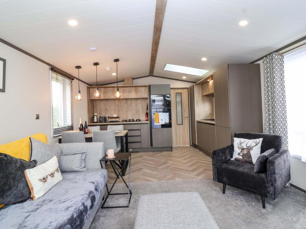 a living room with a couch and a kitchen at Hazelnut Lodge in Chipping Norton