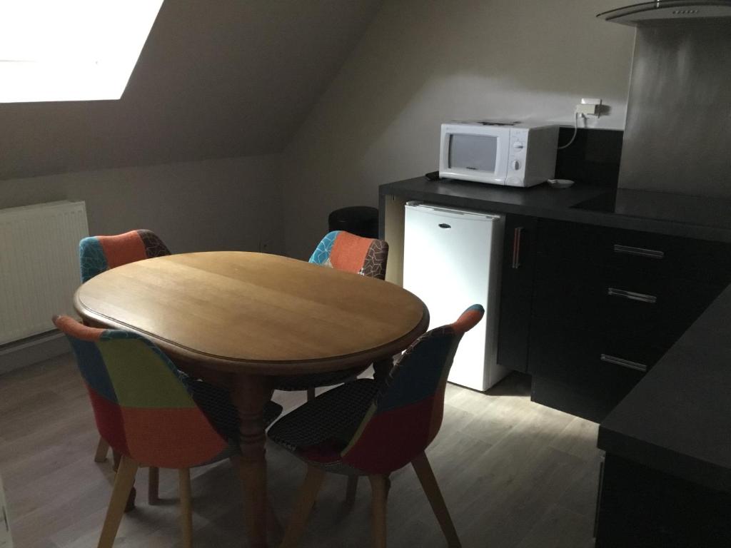 une cuisine avec une table et des chaises et un micro-ondes dans l'établissement Maison 1er étage chéreng 6kms stade Pierre Mauroy 4 personnes, à Chéreng