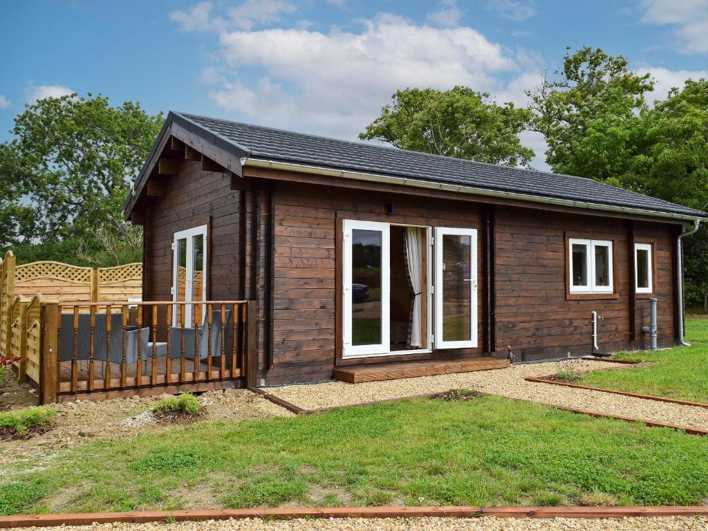 una pequeña casa con una valla en un patio en Pheasant Lodge - Uk33402, en Hungerton