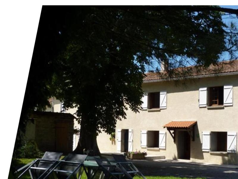 un grand bâtiment avec un arbre devant dans l'établissement maison de campagne, à Le Vernet