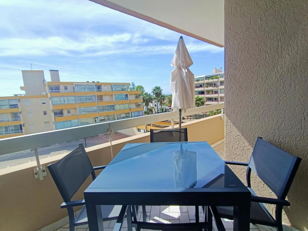une table bleue et des chaises sur un balcon avec un parasol dans l'établissement Canet-en-Roussillon: Charmant T2 avec Clim et Parking, Plage à Proximité! - FR-1-794-163, à Canet