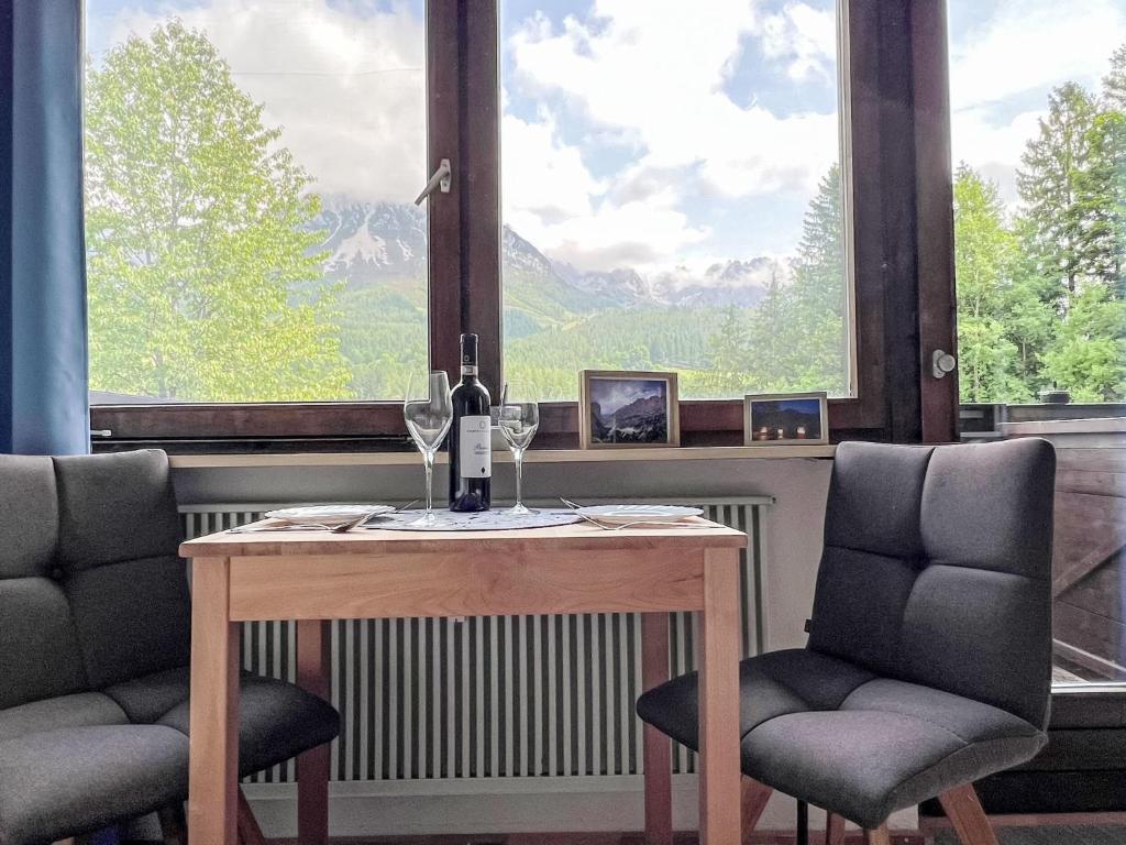 - une table avec des verres à vin et 2 chaises devant une fenêtre dans l'établissement Apartment Studio Esche 2 by Interhome, à Ellmau