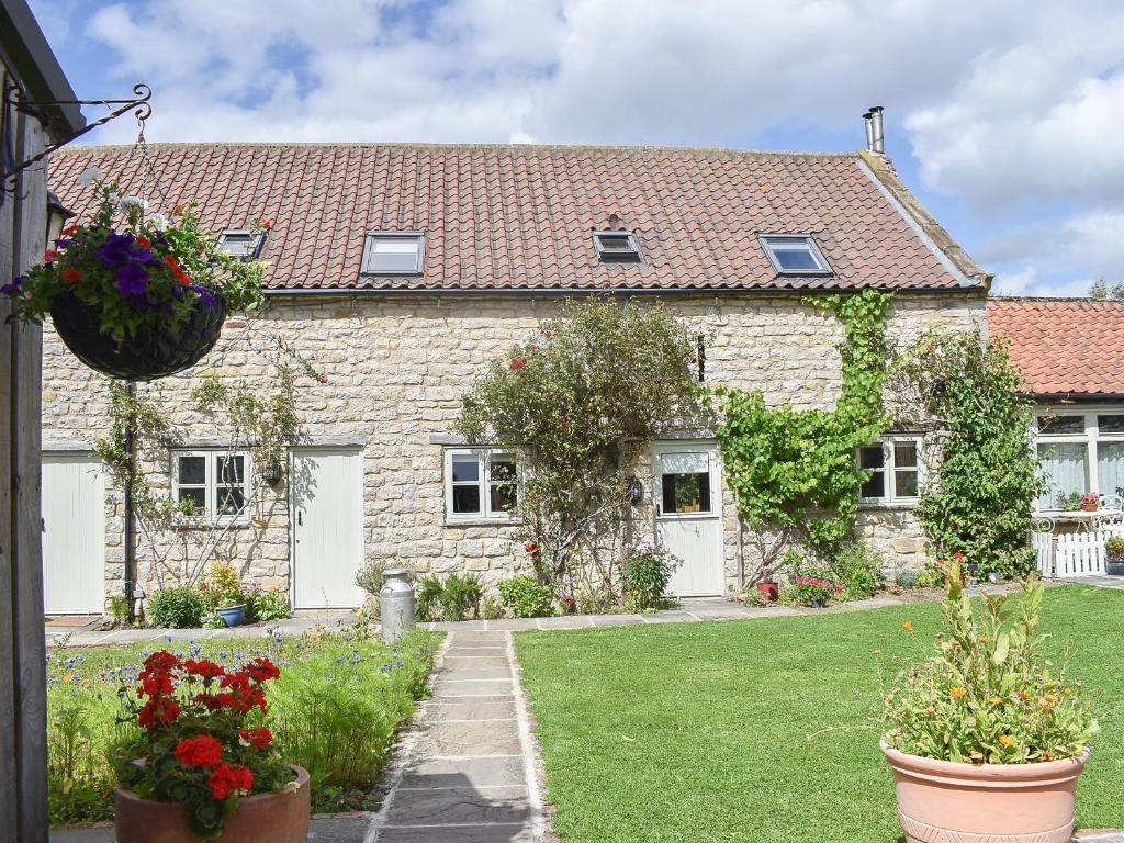 a stone house with flowers in a yard at Fox Cover Cottage in Great Edston