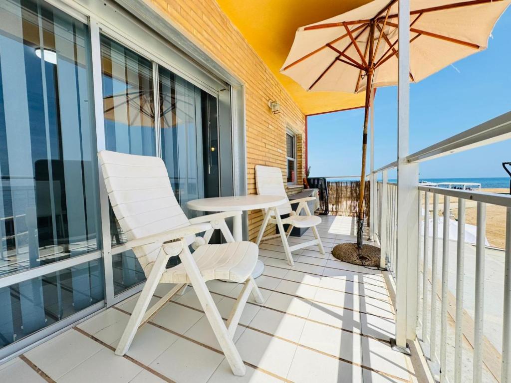 Un balcón con una mesa y sillas y una sombrilla. en Beachfront apartment - La Mata, en Torrevieja