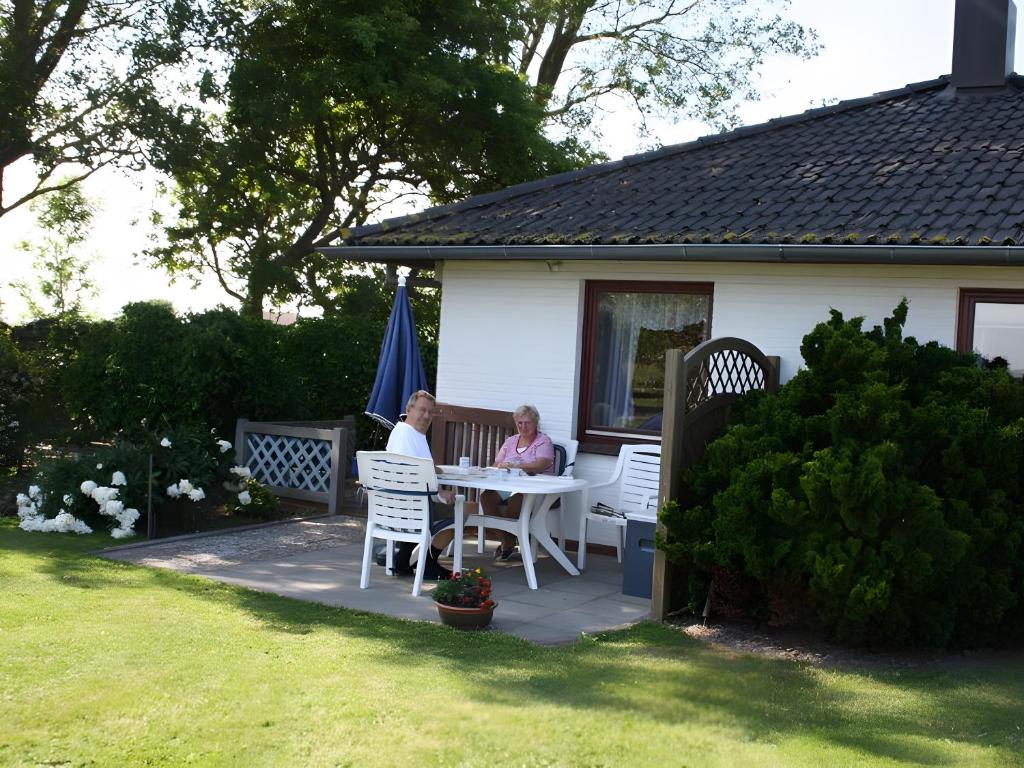 two people sitting at a table outside of a house at Ferienhaus Seewind in Nordstrand