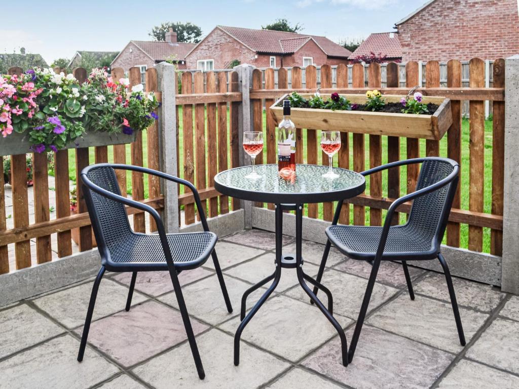 twee stoelen en een tafel met wijnglazen op een patio bij Keepers Retreat, The Annex in Roughton