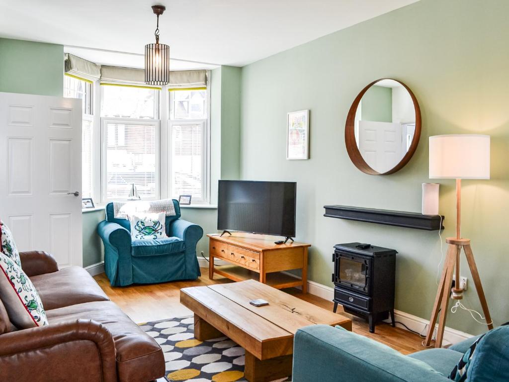 een woonkamer met een bank, een tafel en een tv bij Poppywinkle in Filey