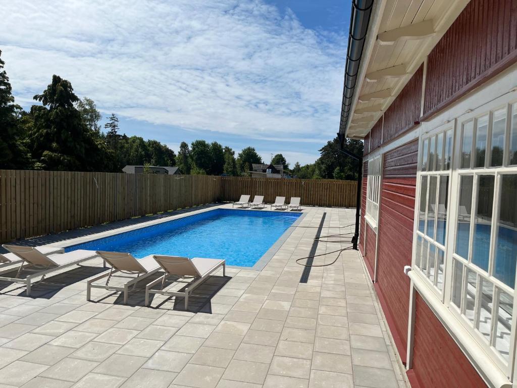 a swimming pool with lounge chairs next to a house at Nybyggd lgh 100m till stranden, 150m till golfbana ,samt gemensam pool och spa in Beddinge