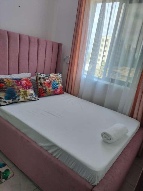 ein Bett mit zwei Kissen und einem Fenster in der Unterkunft Secret serenity homes in Mombasa