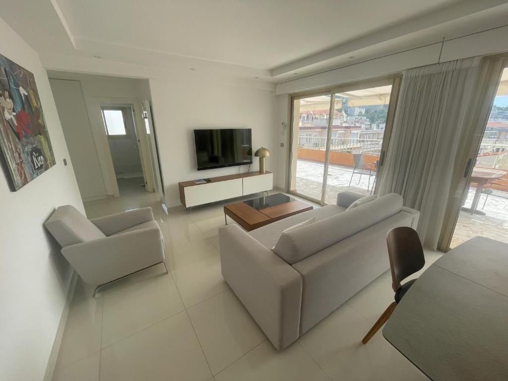 un salon avec un canapé, des chaises et une télévision dans l'établissement Apt Cannes Centre - Proche des Plages et du Palais des festivals - Climatisation - Parking privée, à Cannes