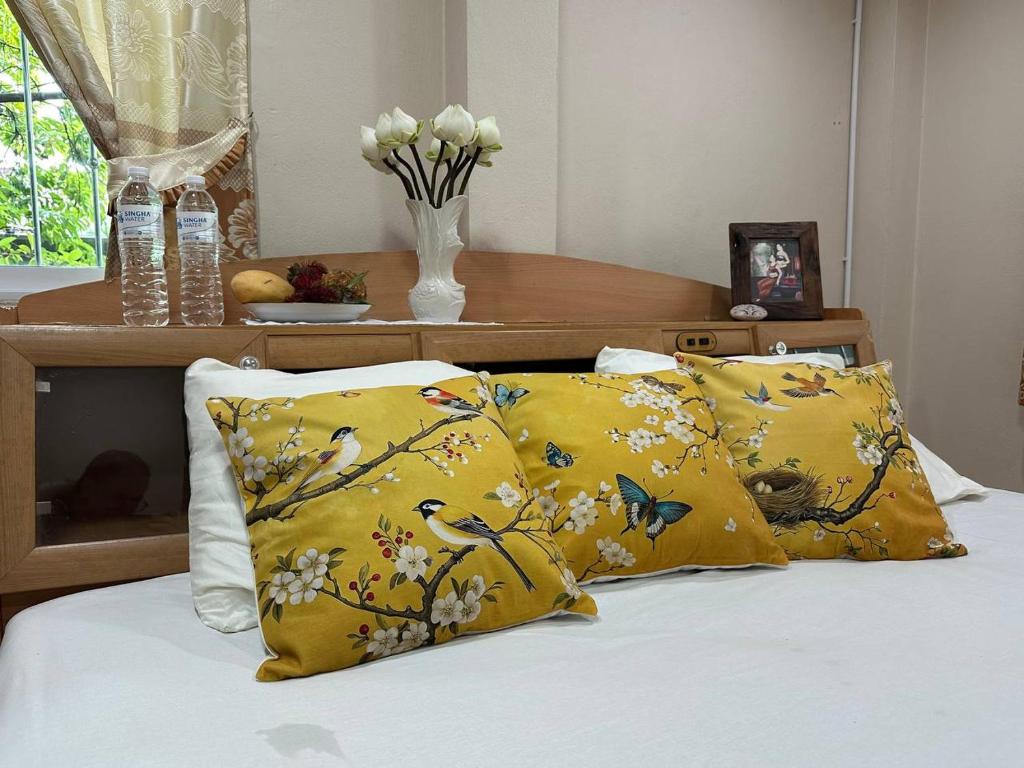 a bed with two yellow pillows and a table at Yoga Bed and Breakfast in Chiang Mai
