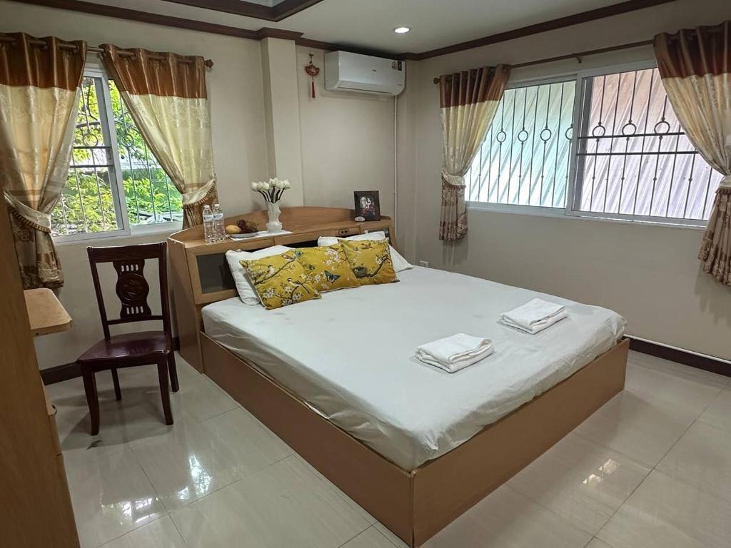 a bedroom with a bed and a chair and windows at Yoga Bed and Breakfast in Chiang Mai