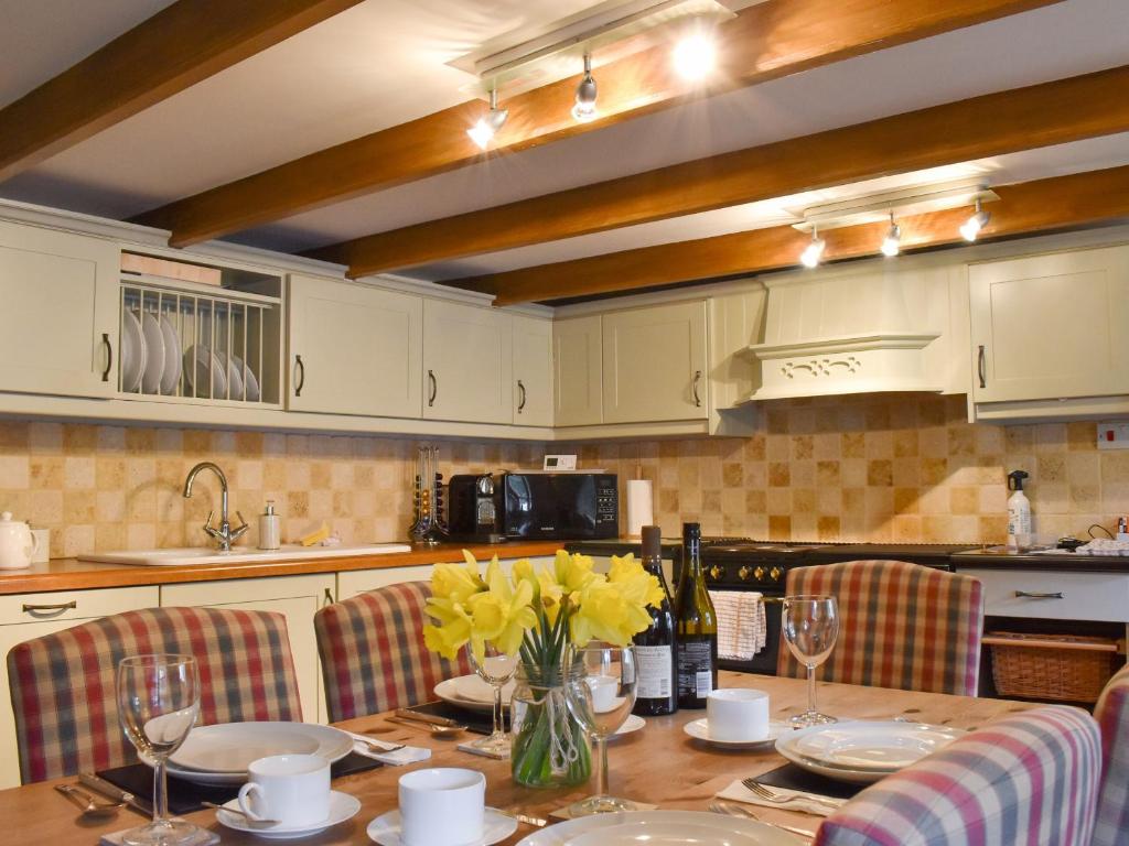 a kitchen with a table with yellow flowers in a vase at Pineview Cottage in Downderry