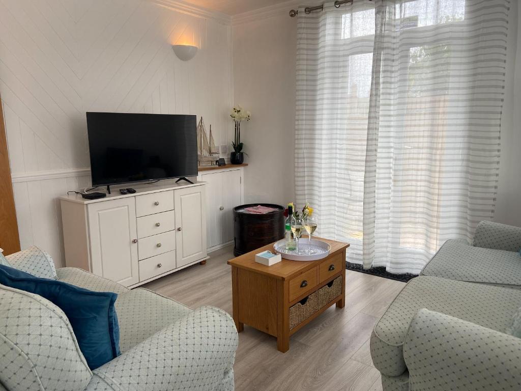 a living room with a tv and a couch and a table at Smile 'N' Wave in Gorleston-on-Sea