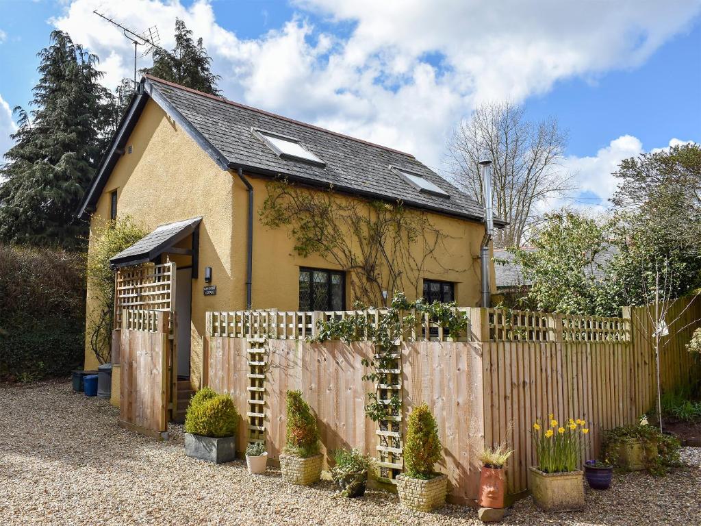 a house behind a wooden fence with a gate at Barn Court Cottage in Washfield